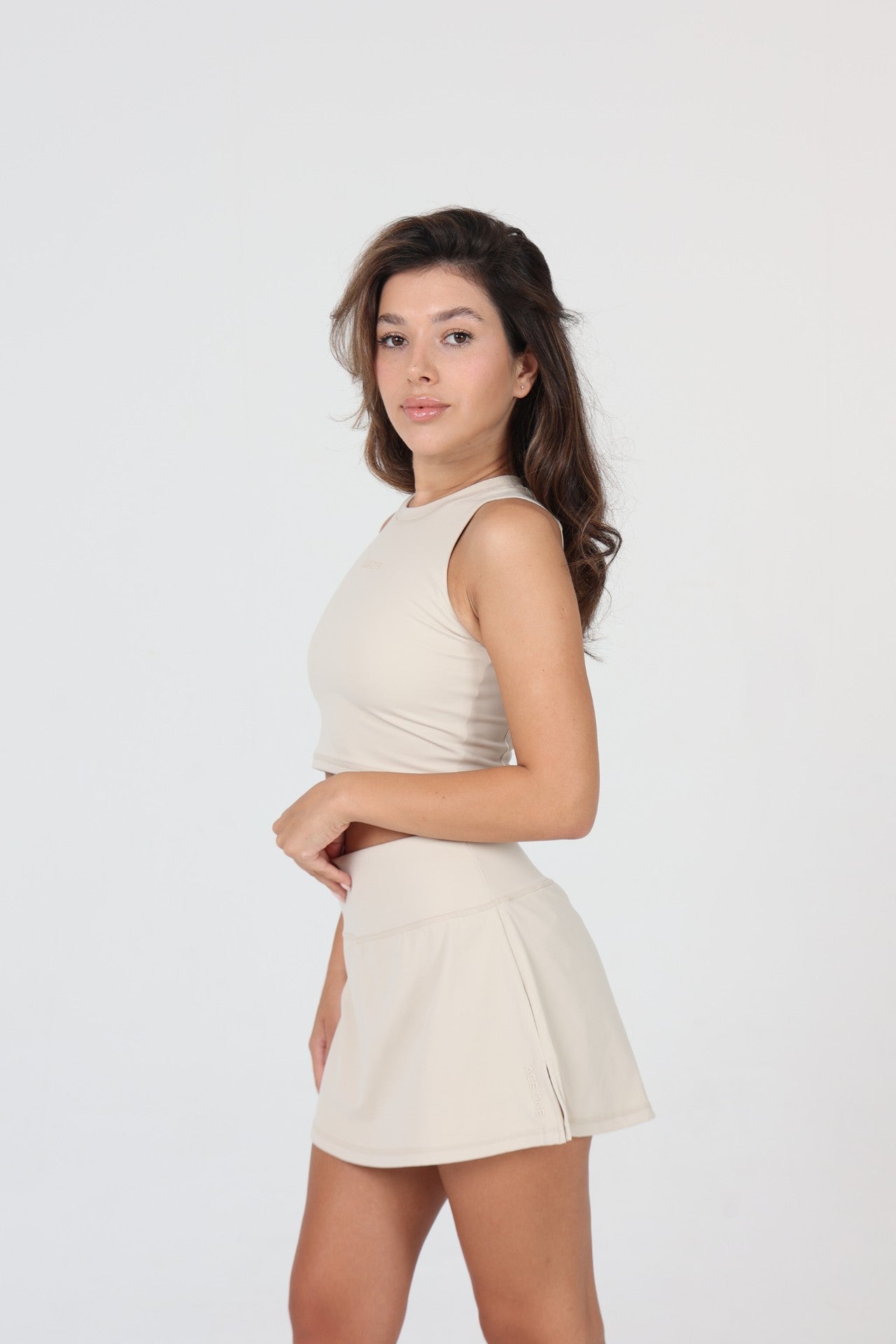 Woman serving in ACE ONE beige padel skort