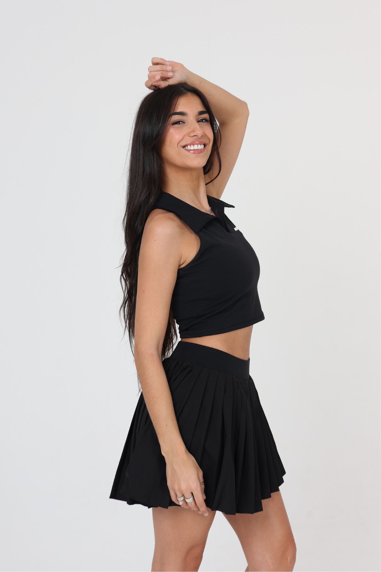 Woman lunging in ACE ONE black pleated padel skirt