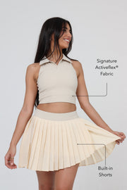 Woman wearing ACE ONE beige pleated padel skirt on court