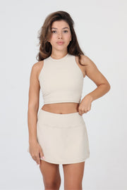 Woman wearing ACE ONE beige high-neck padel tank top outdoor court