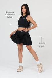 Woman wearing ACE ONE black pleated padel skirt on court